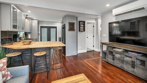 Een moderne keuken met een houten eiland, barkrukken en een ingebouwde televisie.
