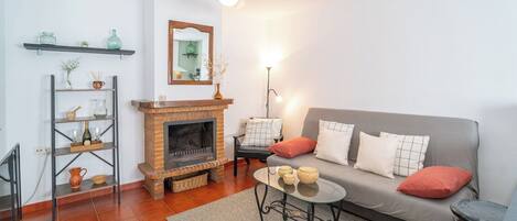 A living room with a fireplace, sofa, coffee table, and shelves.
