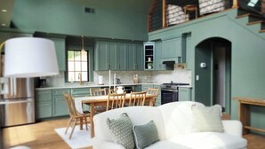 Une cuisine moderne avec des meubles de couleur turquoise, une table à manger et un canapé blanc agrémenté de coussins à motifs.