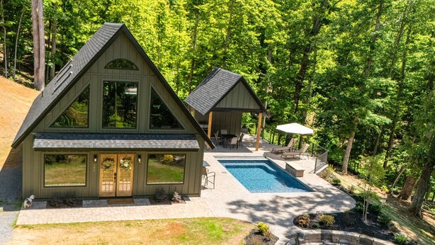 Une maison à deux étages dotée d’une piscine, d’un espace salon extérieur et d’un foyer.