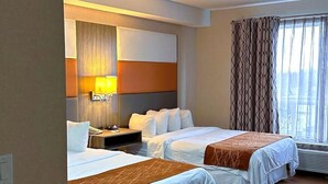 A hotel room with two beds, a bedside table, a lamp, and a window with curtains. - Southfort Inn  (Fort Saskatchewan)