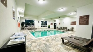 A pool area with lounge chairs, a pool, and a reception desk. - Southfort Inn  (Fort Saskatchewan)