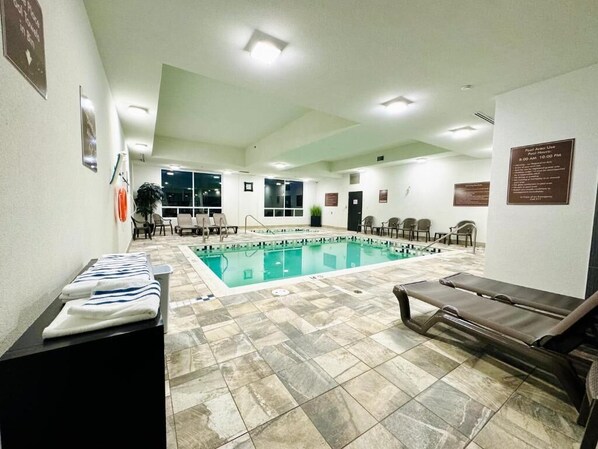 A pool area with lounge chairs, a pool, and a reception desk.