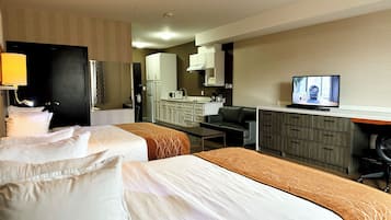 Habitación de hotel con dos camas, un escritorio, televisor, kitchenette y baño.