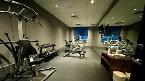 A gym with exercise equipment, a reception desk, and a large window. - Southfort Inn  (Fort Saskatchewan)
