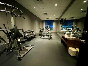 A gym with exercise equipment, a reception desk, and a large window. - Southfort Inn  (Fort Saskatchewan)