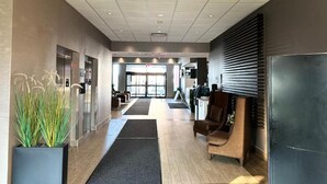 A modern hotel lobby with a reception desk, seating area, and a large window. - Southfort Inn  (Fort Saskatchewan)