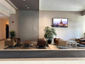A lobby with seating, a large TV, and a plant. - Southfort Inn  (Fort Saskatchewan)