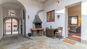 Un interior rústico con chimenea de piedra, muebles de madera y paredes blancas.