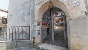 Entrada de un edificio con una reja de hierro forjado, un letrero de no estacionamiento y el número 24 en la pared.