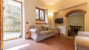 Una sala de estar con sofá, televisor montado en la pared, chimenea y un ventanal grande.