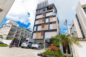 Ein mehrstöckiges Gebäude mit modernem Design, das Beton und Glas kombiniert und einen verschlossenen Eingang hat.