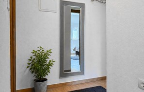 Ein Flur mit einem Blumentopf, einem Spiegel und einer Tür zu einem anderen Raum.