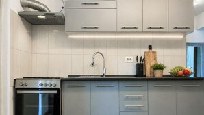 Moderni keittiö, jossa on ruostumattomasta teräksestä valmistetut kodinkoneet, sisäänrakennettu uuni ja hana, jossa on pesuallas.
