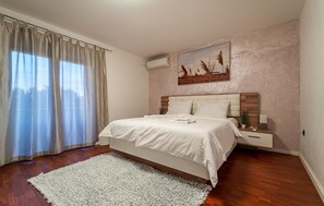 A bedroom with a bed, a nightstand, a wall-mounted air conditioner, and a window with curtains. - Beautiful home in Donje Rastane (Donje Rastane)