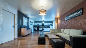 A modern living room with a sofa, ottomans, a coffee table, and a kitchen in the background. - Beautiful home in Donje Rastane (Donje Rastane)