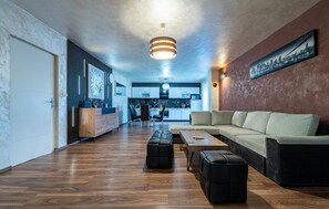 A modern living room with a sofa, ottomans, a coffee table, and a kitchen in the background. - Beautiful home in Donje Rastane (Donje Rastane)