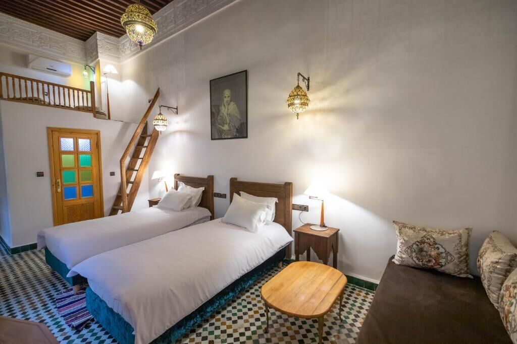 Un dormitorio con dos camas, una mesa de madera, una escalera y un piso con diseño.