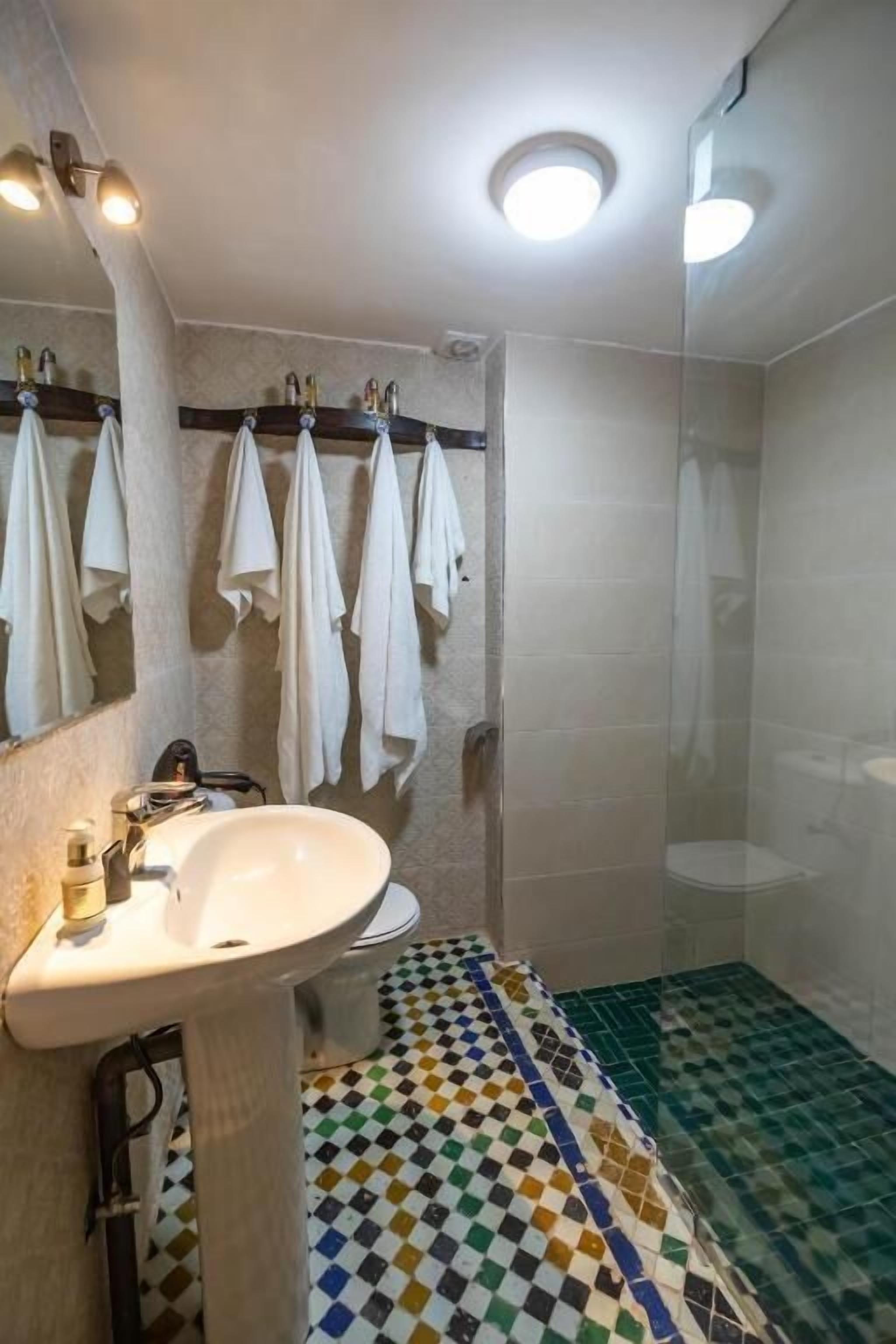 Un baño con lavamanos blanco, espejo y ducha.