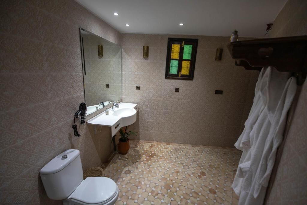 A bathroom with a toilet, sink, and mirror.