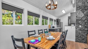A dining area with a wooden table and chairs, a chandelier, and a kitchen in the background. - Marina View Cabin - Boat Slip - Sleeps 11 - Pets OK (Bass Lake)