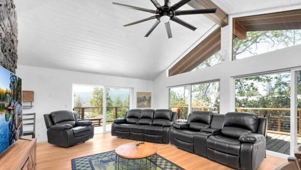 A spacious living room with a large sectional sofa, a coffee table, and a ceiling fan. - Marina View Cabin - Boat Slip - Sleeps 11 - Pets OK (Bass Lake)