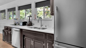 A modern kitchen with a stainless steel refrigerator, a built-in dishwasher, a double sink, and a window above the sink. - Marina View Cabin - Boat Slip - Sleeps 11 - Pets OK (Bass Lake)