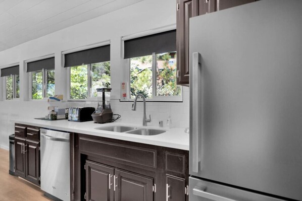 A modern kitchen with a stainless steel refrigerator, a built-in dishwasher, a double sink, and a window above the sink. - Marina View Cabin - Boat Slip - Sleeps 11 - Pets OK (Bass Lake)
