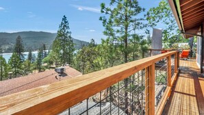 A wooden deck with a view of a lake and mountains. - Marina View Cabin - Boat Slip - Sleeps 11 - Pets OK (Bass Lake)