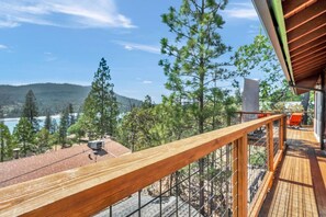 Una terraza de madera con vistas a un lago y montañas.