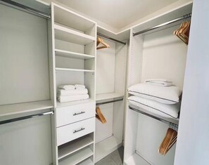 Ein begehbarer Kleiderschrank mit offenen Regalen, Kleiderstangen und Schubladen.