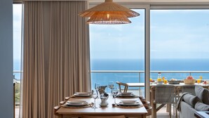 Een eetgedeelte met een tafel voor twee personen, een rieten stoel en uitzicht op zee.