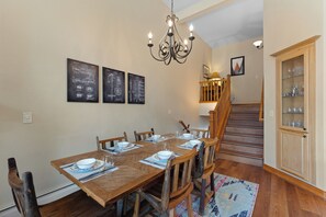 A dining area with a wooden table set for four, a chandelier, and framed blueprints on the wall. - Downtown WP River Villa 522 I Private Hot Tub I Great Views I Work Station I Discounted Attractions (Winter Park)