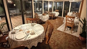 An outdoor dining area with round tables, chairs, and a tiled floor.
