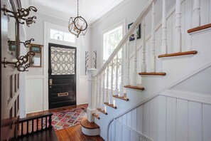 Eine Treppe mit weißen Geländern und Holzstufen, die zu einer schwarzen Tür mit dekorativen Glassfeldern führt.