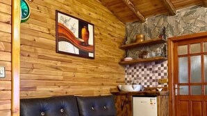 A wooden interior with a leather sofa, a kitchen area, and a patterned rug.