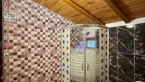 A bathroom with a checkered tile wall, a toilet, a sink, and a shower with circular cutouts.