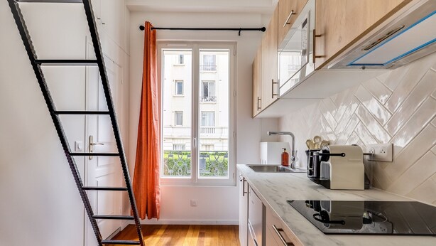 A compact kitchen with a window, a pull-out shelf, and a modern stove. - Studio 2P - Roland Garros Stadium and Bois de Boulogne (Paris)