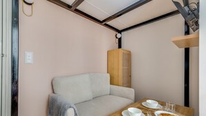 A cozy room with a sofa, a wooden table with a plate of food, and a small heater. - Studio 2P - Roland Garros Stadium and Bois de Boulogne (Paris)