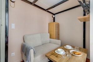A cozy room with a sofa, a wooden table with a plate of food, and a small heater. - Studio 2P - Roland Garros Stadium and Bois de Boulogne (Paris)
