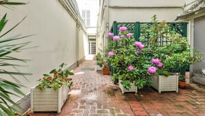 Een smalle steeg met plantenpotten en een groen hek.