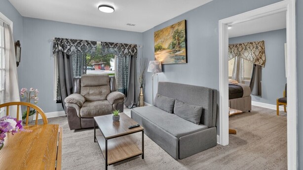 A modern living room with a grey sofa, a leather armchair, and a wooden coffee table. - Cozy Private Home w Fire Pit Near Downtown! (Kalamazoo)