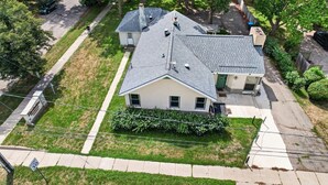 A residential house with a sloped roof, a front porch, and a driveway. - Cozy Private Home w Fire Pit Near Downtown! (Kalamazoo)