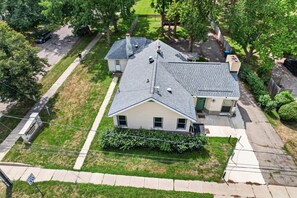 A residential house with a sloped roof, a front porch, and a driveway. - Cozy Private Home w Fire Pit Near Downtown! (Kalamazoo)
