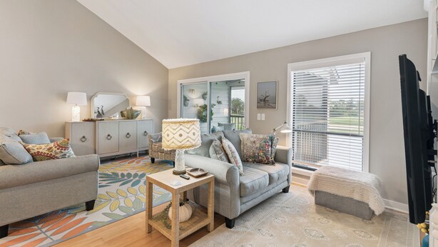 A living room with two sofas, a coffee table, a side table, and a window with blinds. - Coastal Sea Palms Retreat | Golf Views + Screened Porch (Saint Simons Island)