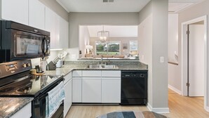 A modern kitchen with a dishwasher, stove, and microwave. - Coastal Sea Palms Retreat | Golf Views + Screened Porch (Saint Simons Island)