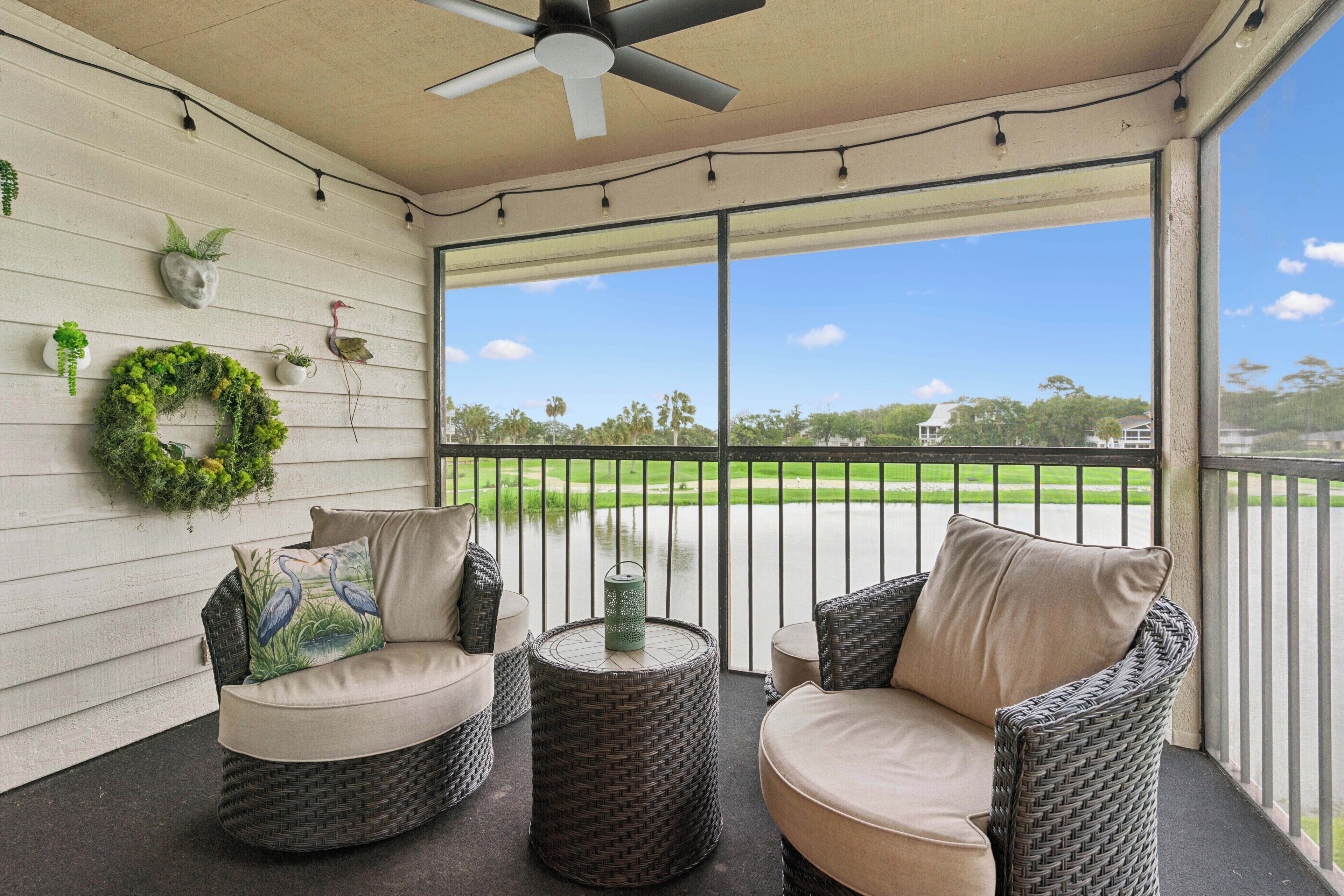A covered porch with wicker furniture, a ceiling fan, and a view of a golf course.