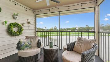 A covered porch with wicker furniture, a ceiling fan, and a view of a golf course.