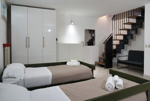 Une chambre d’hôtel comprenant un lit, une armoire, un coin salon et un escalier.