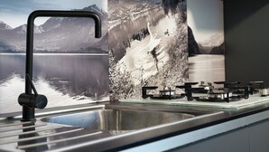 Une cuisine équipée d’un évier en acier inoxydable, d’un robinet moderne et d’une cuisinière à gaz.